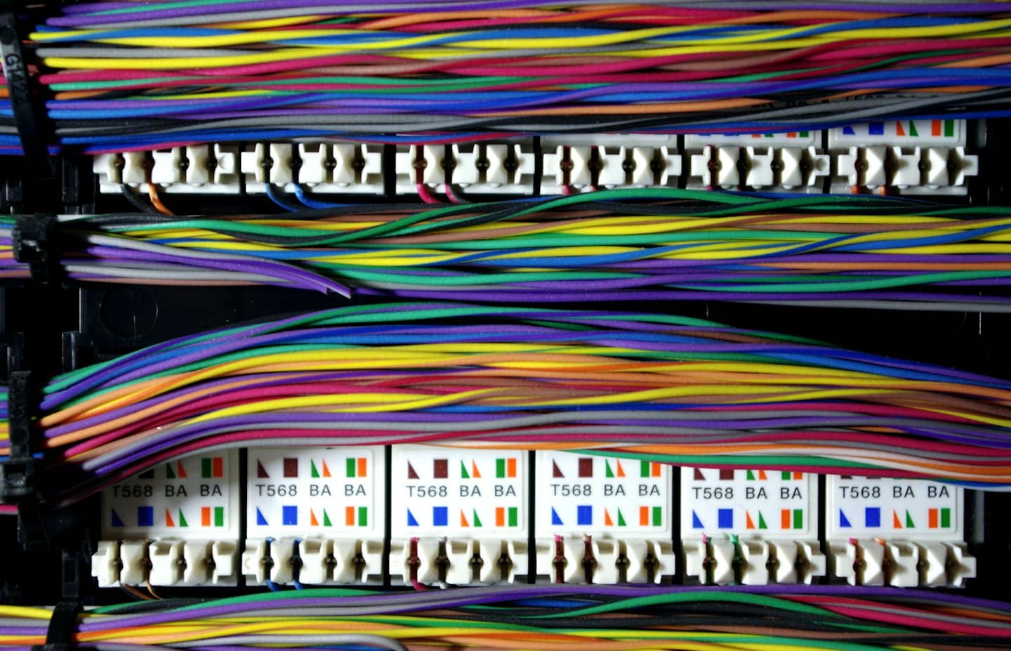Neatly bundled colorful network cables connected to a patch panel.